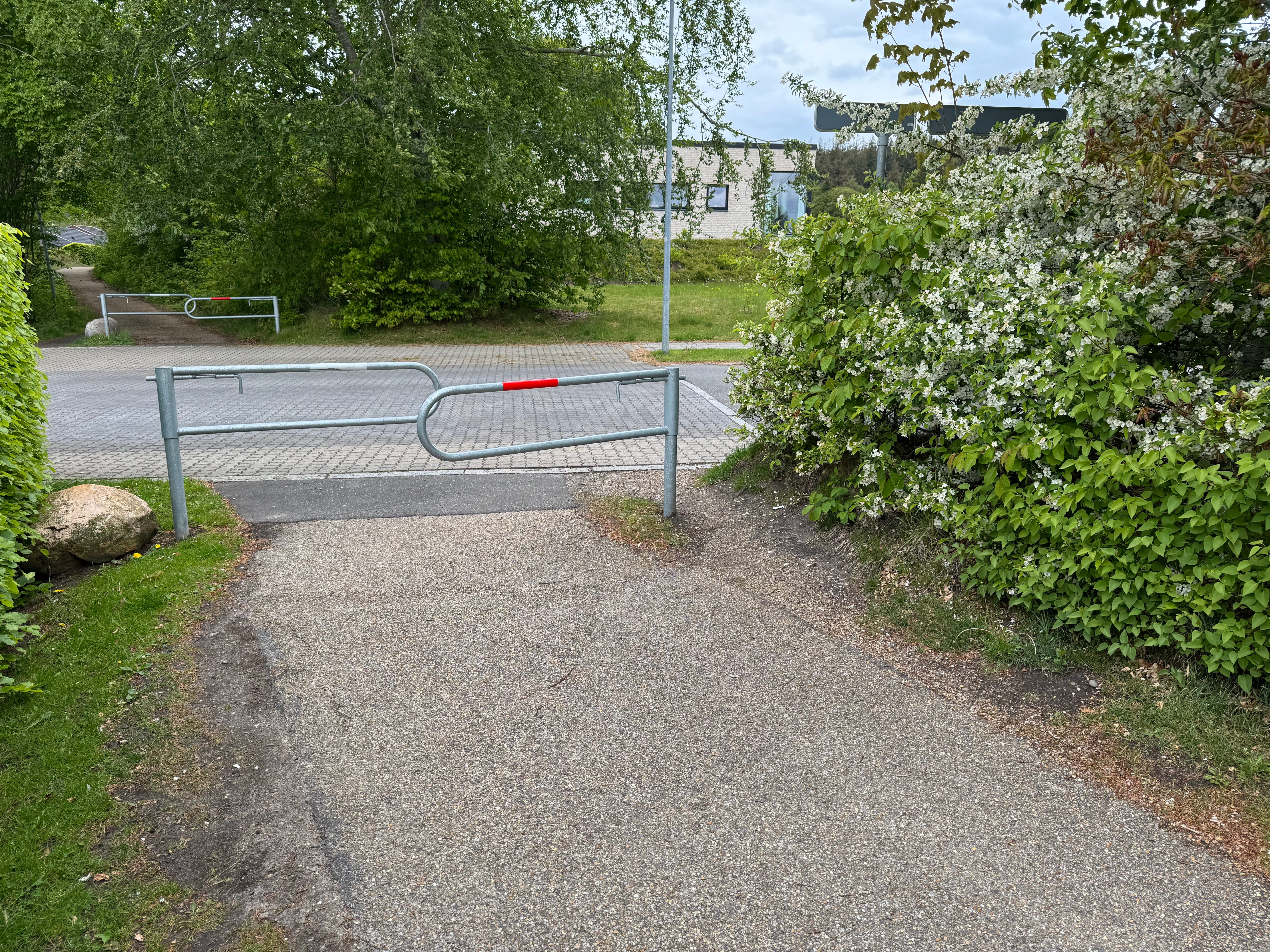 Bom 3 ved den nordlige udmunding. Drejelig spærrebom i galvaniseret stål med rød refleksmarkering centralt. Bag bommen ses villavejen Hjortespringet
