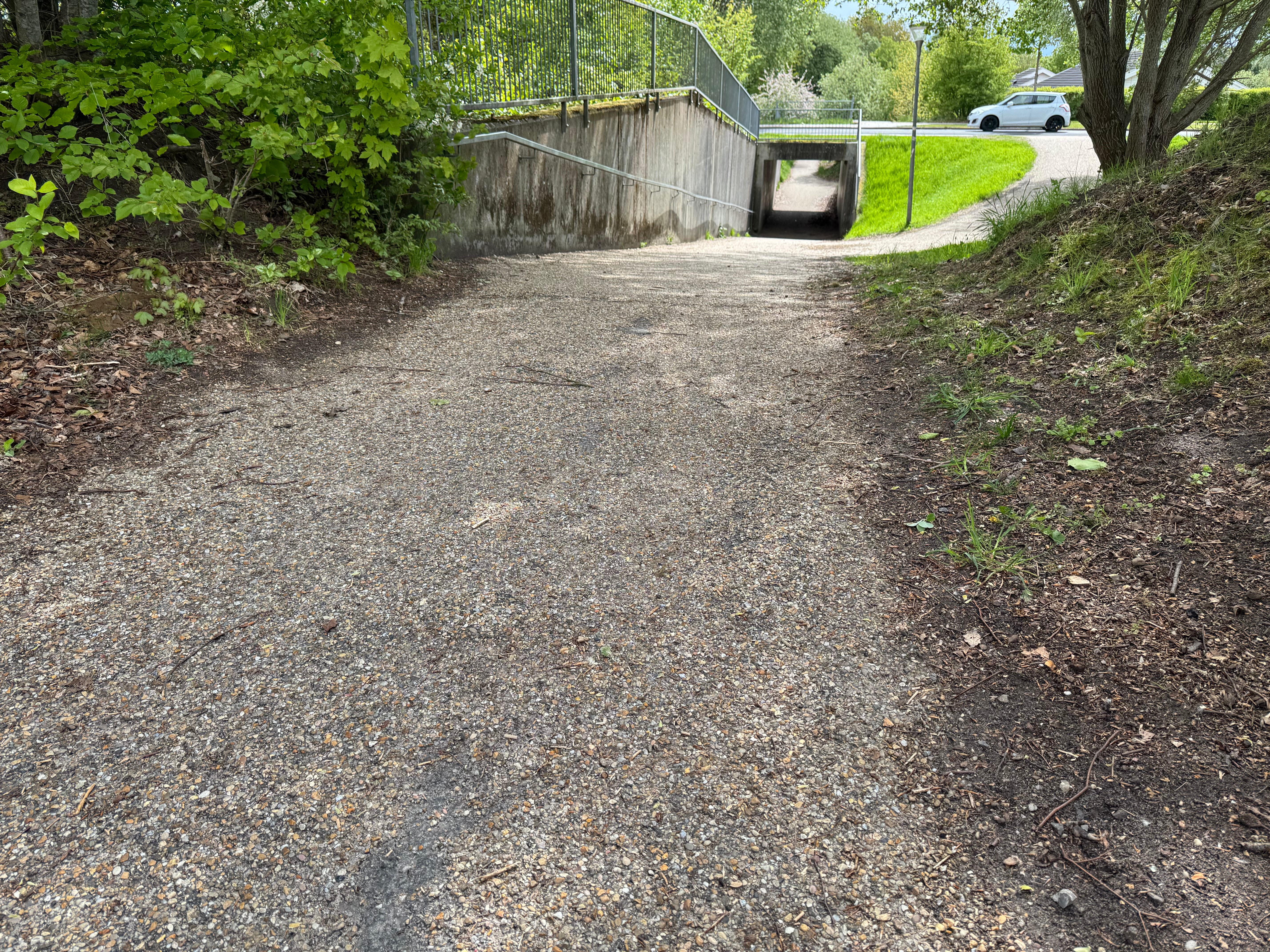 Cykelstiens nordlige ende set fra syd, med tunnellen under Gunilshøjvej i baggrunden. Asfaltoverfladen synlig i forgrunden